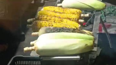Bu görüntü, bir sokak yemeği satıcısını kömür ızgarasında mısırı ustalıkla kızartırken yakalıyor. Mısır tanelerinin dönüşümüne tanık olun.