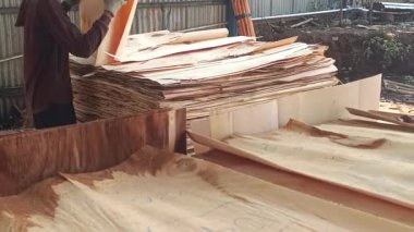 Bir zanaatkar titizlikle bir kaplama işleme fabrikasında çalışıyor. Çarşafları dikkatlice düzenliyor, kusurları kontrol ediyor ve onları bir sonraki adıma hazırlıyor..