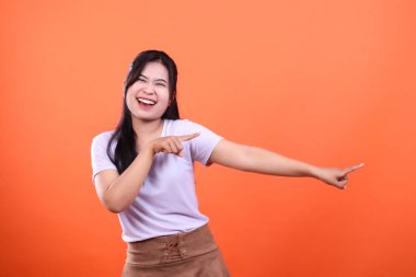 Bir insan gülümser ve turuncu bir arka planda izole edilmiş iki farklı yönü gösterir. Kişi beyaz gömlek ve kahverengi etek giyiyor..