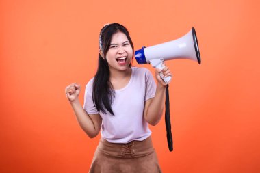 Heyecanını ifade ederken elinde beyaz ve mavi bir megafon tutan biri. Turuncu bir arka planda izole edilmiş..