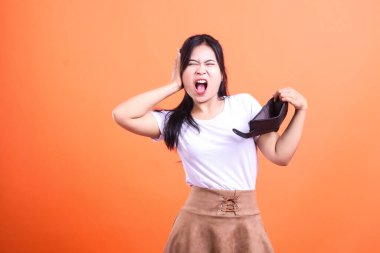 Turuncu arka planı olan boş bir siyah cüzdan tutan bir insan. Kadın, beyaz tişört ve kahverengi etek giyiyor. Kişi siyah saçlı ve bağırıyor..