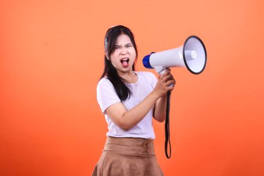 Turuncu arka planda izole edilmiş beyaz ve mavi bir megafona bağıran bir kişi var. Beyaz bir gömlek ve kahverengi bir etek giyiyor..