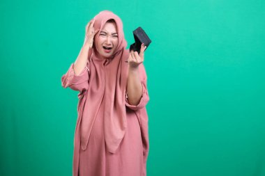 Başörtüsü içinde genç bir kadın perişan görünüyor. Elinde boş bir yüzük kutusu var. Yeşil arka planda izole edilmiş derin bir şok ve üzüntü ifade ediyor. Sahne mali ya da evlilik konularındaki hayal kırıklığını gösteriyor.