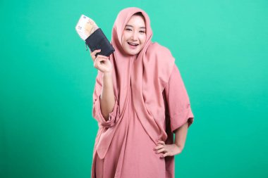 Avro banknotlarıyla dolu bir cüzdanı olan genç bir İslami işkadını yeşil bir arka planda güvenle gülümsüyor. Finansal kontrol ve refah gösteriyor, yeşil arka planda izole edilmiş..