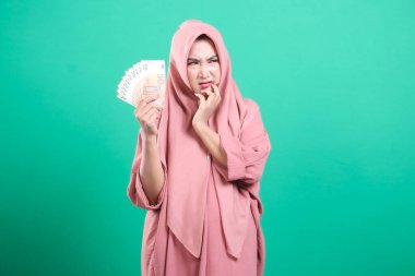 Ekonomik zorlukları ve yeşil arka planda izole edilmiş mali istikrarsızlığı yansıtan, avro banknotları taşıyan düşünceli genç bir kadın.