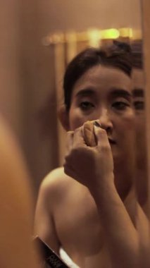 Kadınların cilt bakımı ritüeli, genç bir kadının banyo aynasının önüne yüz bakımı uygulaması.