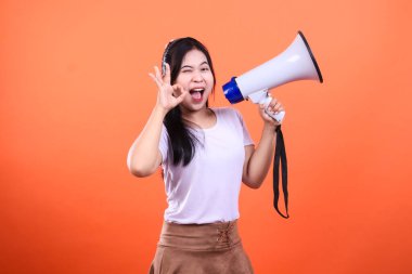 Elinde megafonla gülümseyen ve sol eliyle 