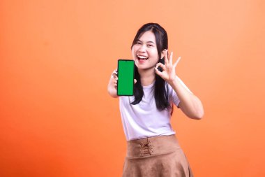 Bir kadın gülümsüyor ve elinde yeşil ekranlı bir cep telefonu ile 