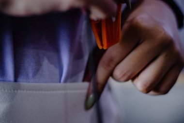 Yakından bakınca, bir modeli titizlikle monte eden, detaylara ve hassasiyete vurgu yapan eller görülüyor. Yumuşak bir zemin üzerinde parlak turuncu plastik parçaları hobisinin karmaşıklığını vurgular.