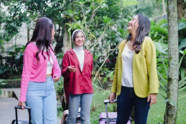 Üç şık, neşeli genç bayan, bavullarıyla geliyorlar, kahkahalar ve hikayelerini açık havada paylaşıyorlar yemyeşil çiçeklerle çevrili. Hak edilmiş bir tatile ve biraz kaynaşmaya hazırım..