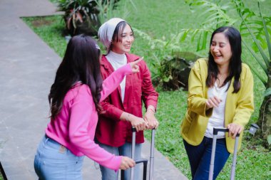 Üç neşeli bayan arkadaş, biri tesettür takıyor, birlikte heyecan verici bir yolculuğa çıkıyorlar, kahkaha ve neşeyi paylaşıyorlar, valizleriyle birlikte manzaralı bir yeri keşfederken..