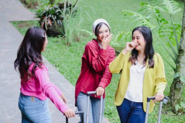 Üç arkadaş açık havada bavullarıyla bir anlık eğlencenin tadını çıkarıyorlar. Yolculuklarına çıkarken ifadeleri mutluluk ve dostluk saçıyor..