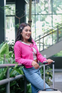 Cazip bir kadın yolculuğu sırasında duraksar. Işıl ışıl gülüşü seyahatin heyecanını yansıtır. Fuşya rengi bir hırka giyip bekliyor. Gezgin ruhunu kucaklıyor..