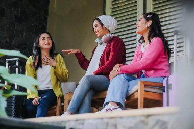 Üç gülümseyen bayan arkadaş seyahat etmeden önce neşeli anlar ve kahkahalar paylaşıyorlar. Bu seyahat arkadaşları tatillerini hikayelerini anlatarak ve anılarını anlatarak kutluyorlar..