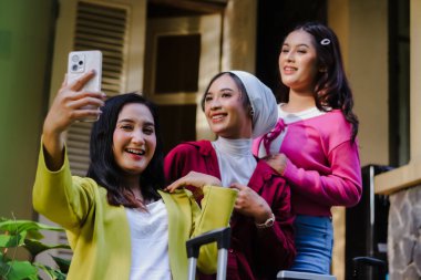 Üç hayat dolu kadın, somutlaşmış arkadaşlık, akıllı bir telefonla selfie çekiyorlar. Yolculuğa hazırlar, gülümsüyorlar ve varış noktalarını görmek için heyecanlılar, neşeli ve mutlu..