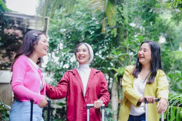 Üç neşeli kadın, biri tesettürlü, bavullarla keyifli bir anı paylaşıyor, harika bir yolculuğa hazır. Yaklaşan maceraları için mutluluk ve beklenti saçıyorlar..