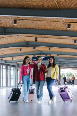 Havalı, modern bir ulaşım merkezinden güvenli bir şekilde geçen üç modaya uygun genç kadın yolculukları için heyecanlılar ve unutulmaz anlar yaratıyorlar..