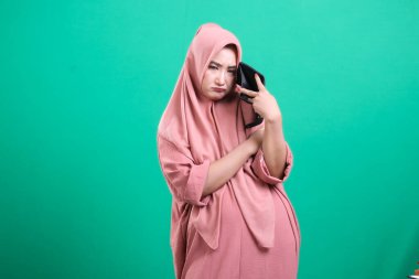 Hayal kırıklığına uğramış bir kadın, mali kriz sırasında boş bir cüzdan gösteriyor, yeşil arka planda izole edilmiş, bu görüntü, bütçe sorunlarını ve kötü ekonominin sonuçlarını yansıtıyor..