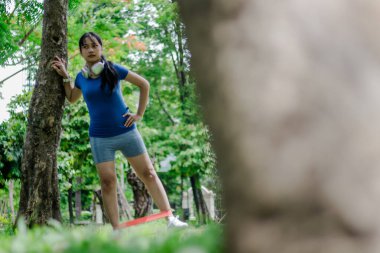 Aktif bir kadın dışarıda egzersiz yapmak için direniş bandı kullanır. Fiziksel sağlık ve zindeliği teşvik eder. Egzersiz alışkanlığı onu enerjik tutuyor. Sabahleyin parkta..
