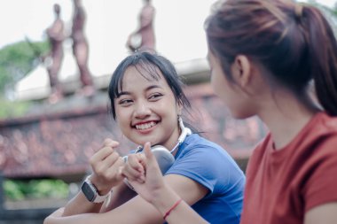 İki genç kadın bir anı paylaşıyor, gülümseme ve sıcaklıkla verilmiş serçe parmak sözü, güçlü bir dostluk bağını simgeliyor. Sabahleyin parkta..