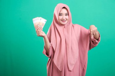 Çekici, tesettürlü genç Müslüman bir kadın. Avro banknotlarını gülümseyerek sunuyor. Finansal büyümeyi destekliyor..