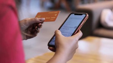 Çevrimiçi ödeme yapmaya hazır, elinde bir kredi kartı ve akıllı telefon olan birinin fotoğrafını çek. E-ticaret, dijital bankacılık ve modern alışveriş kavramı.