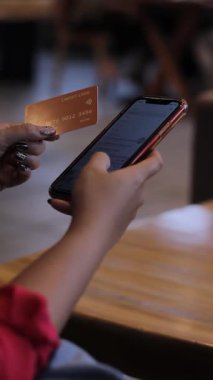 Bir kişinin elinde kredi kartı ve akıllı telefon ile çevrimiçi ödeme yapmaya hazır bir şekilde elini kapatması. E ticaret ve dijital işlemler kavramı.