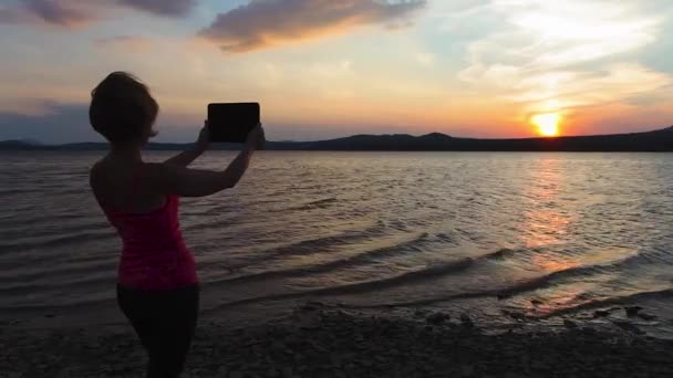Дівчина, захід сонця, гірське озеро, телефон — стокове відео