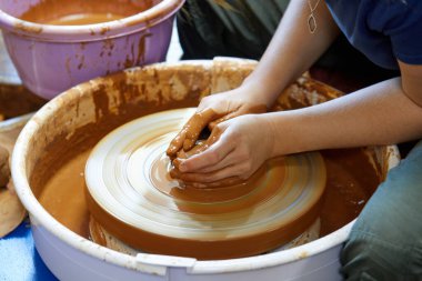 Çömlekçinin tekerinde çömlek yapan bir çömlekçinin elleri.