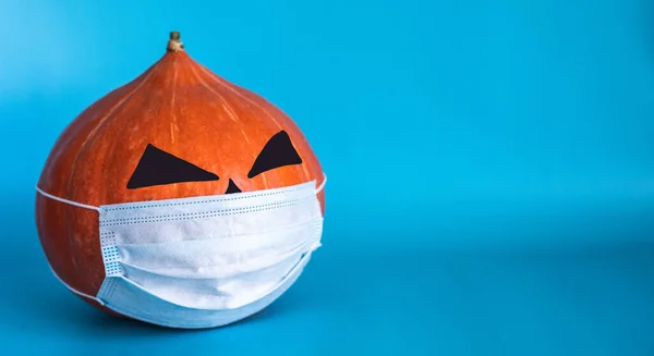 halloween pumpkin in medical mask from COVID-19 on a blue background