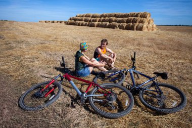 Hen kadın ve erkek tarlada dinleniyor. Bisikletlerin yanına otur.