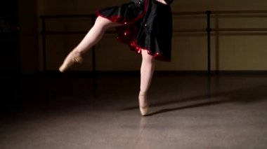 Genç zarif balerin, arka planda ışıkla karanlıkta dans eden klasik balerin unsurları. Karanlıkta genç ve güzel bir balerin. Stüdyoda bale çalışması.