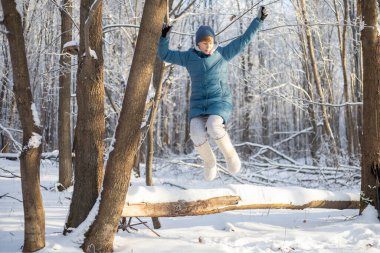 Kız ormandaki devrilmiş bir ağacın üzerinde dinleniyor. Açık hava aktiviteleri. Kışın ormanda yürü.