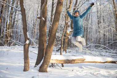Kız ormandaki devrilmiş bir ağacın üzerinde dinleniyor. Açık hava aktiviteleri. Kışın ormanda yürü.