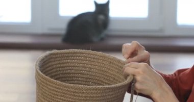 Kadın, çevre dostu malzemelerden örgü örüyor. Ev dekorasyonu için jüt iplik. Ev hobisi kalın duvarlı halat sepetleri örmek. İç mekanda el işi. Örgü jüt ve ip sepetleri..