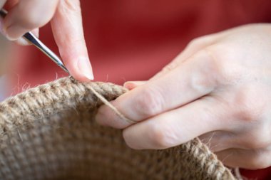 Kadın, çevre dostu malzemelerden örgü örüyor. Ev dekorasyonu için jüt iplik. Ev hobisi kalın duvarlı halat sepetleri örmek. İç mekanda el işi. Örgü jüt ve ip sepetleri..