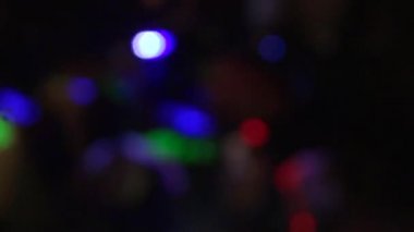 Dans pistindeki neon ışıkları. Bulanık bokeh. İnsanlar dans pistinde zıplıyor ve ellerini sallıyorlar. Eğlence, geçmiş ve parti konsepti