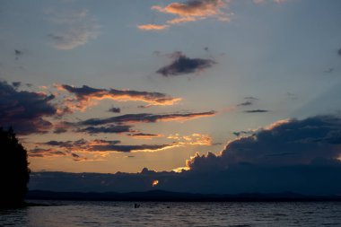 Gün batımında dağ gölü. Yat dalgalarda sallanıyor. Gün batımında bir kızın silueti