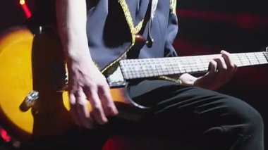 Altın dekoru olan ceketli bir adam gece kulübünde solo bas gitar çalıyor. Tutkulu müzisyen rock festivalinde telli çalgı çalar