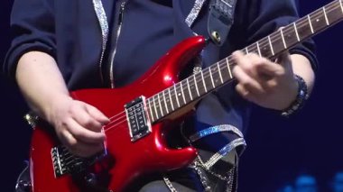Şov kostümlü adam gece kulübünde elektro gitar çalıyor. Yetenekli gitarist festivalde müzik grubuyla birlikte sahnede şarkı söylüyor