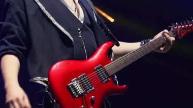 Yetenekli gitarist yakın planda rock konserinde bas gitar çalıyor. Müzisyen konser sahnesinde elektrikli enstrümanla müzik çalar.