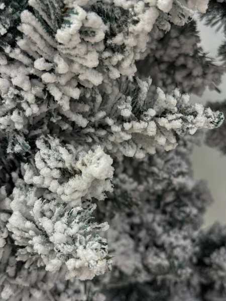 Close-up detailed view of artificial Christmas tree branches with abundant snow