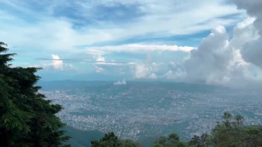 Dramatik bulutlu bir gökyüzünün altında geniş bir şehir vadisinin sağındaki panoramik hava manzarası. Caracas, Venezuela - Yüksek binalar ve yoğun metropol alanı