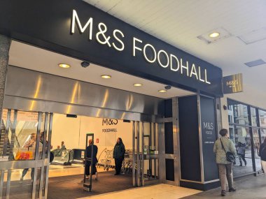 Londra, İngiltere - Temmuz 06 2025: Müşteriler, popüler bir İngiliz bakkal ve gıda perakendecisi olan Marks ve Spencer Foodhall 'ın girişindeki otomatik cam kapılardan içeri giriyor