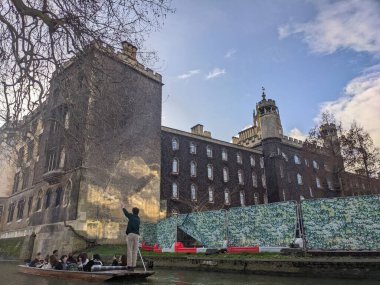 Cambridge, Birleşik Krallık - 31 Ocak 2026: Geleneksel bir tekneyle kayan yolcular, açık bir kış öğleden sonra saatlerinde St. Johns Koleji New Court 'un gotik taş duvarlarını aşarak Cam Nehri boyunca süzülüyorlar