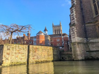 Cambridge, İngiltere - 31 Ocak 2026: Nehir kamerasından alçak açı St. Johns Koleji 'nin tuğla duvarlarını açık mavi kış gökyüzü altında gösteriyor