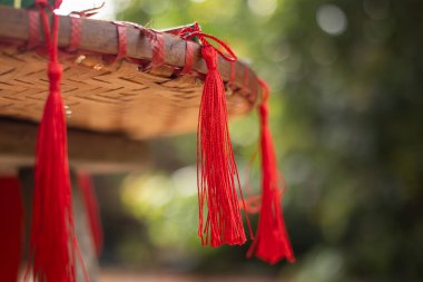 El yapımı bambu tepsinin kenarında asılı canlı kırmızı püskülleri kapayarak Asyalı şenlik desenli bir desen oluşturur.