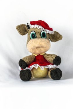 İneğin içindeki el yapımı Amigurumi bebeği kırmızı elbise ve şapkayla oturuyor..