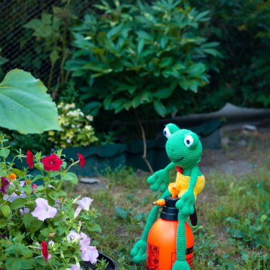 El yapımı Amigurumi bebek kurbağası bahçede böceklerle savaşıyor..