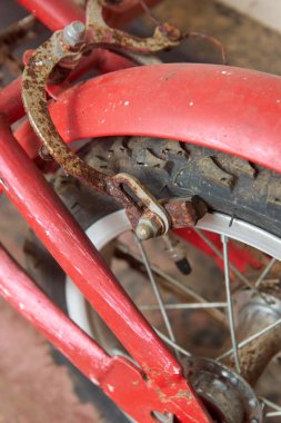 Kırmızı bisiklette paslı arka tekerleğin yakın çekimi ve şiddetli aşınma ile fren mekanizması, dikey yönelimde klasik ulaşım bozunma kavramına yumuşak odaklanma